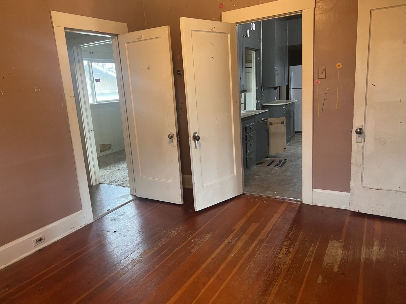 Room inside the Medford house with original hardwood floors, white trim, and doors opening toward the kitchen